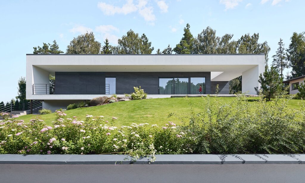 Front elevation of Villa AJ, a minimalist modern house with clean horizontal lines, large terrace, and landscaped garden, designed by NG Architects