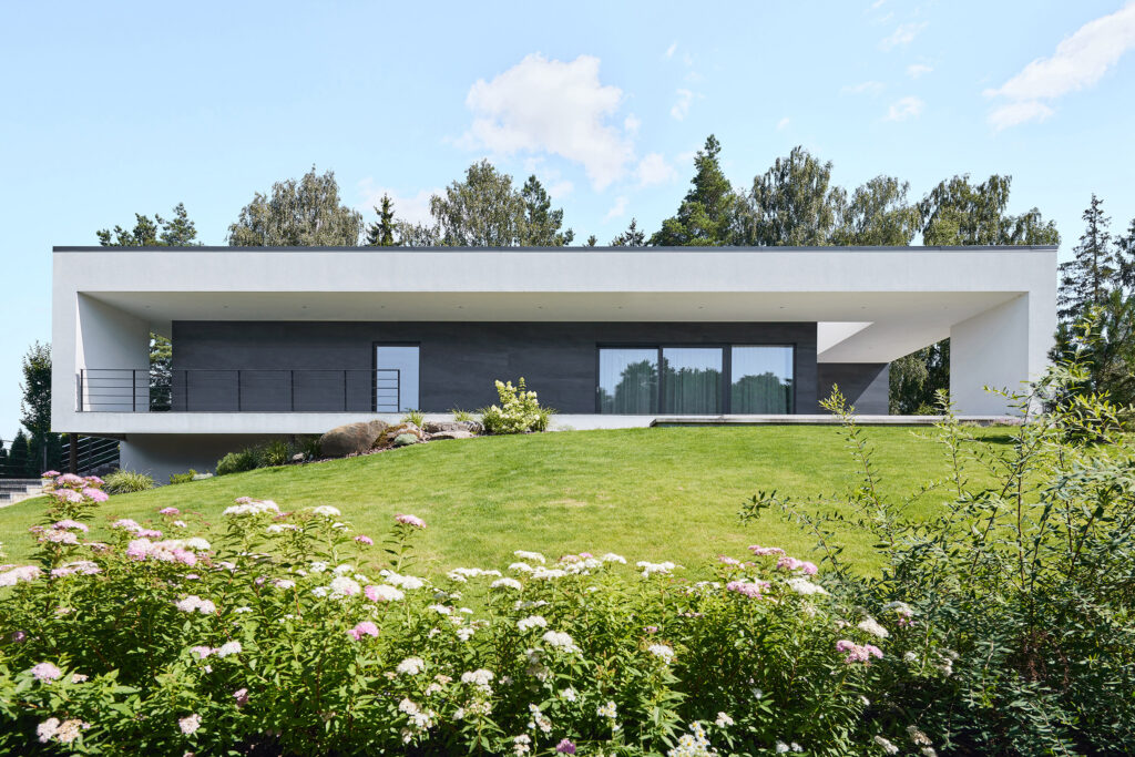 Daytime front elevation of Villa AJ with minimalist horizontal architecture, recessed terrace and landscaped garden, designed by NG Architects