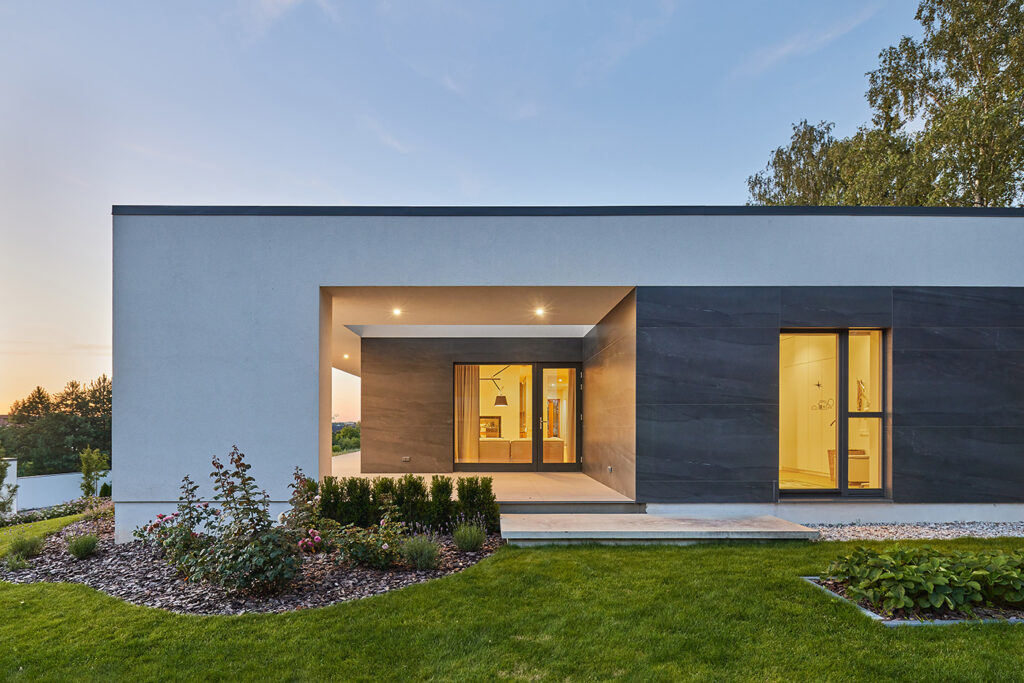 Evening exterior of Villa AJ showing the recessed living room terrace with warm interior lighting and minimalist façade, designed by NG Architects