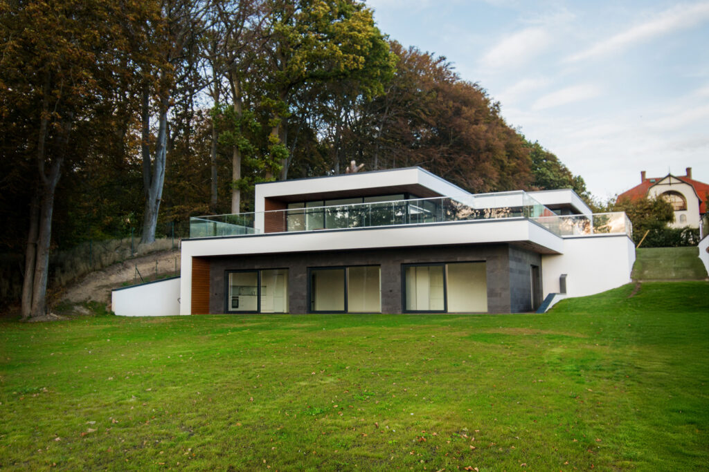 Modern single-storey villa integrated into sloped landscape with terraces and glass railings in Sweden