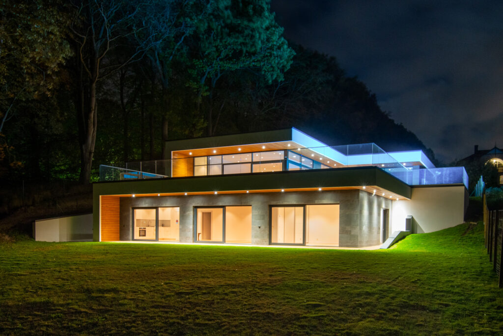Modern single-storey villa in Sweden at night with illuminated glass façade and terrace