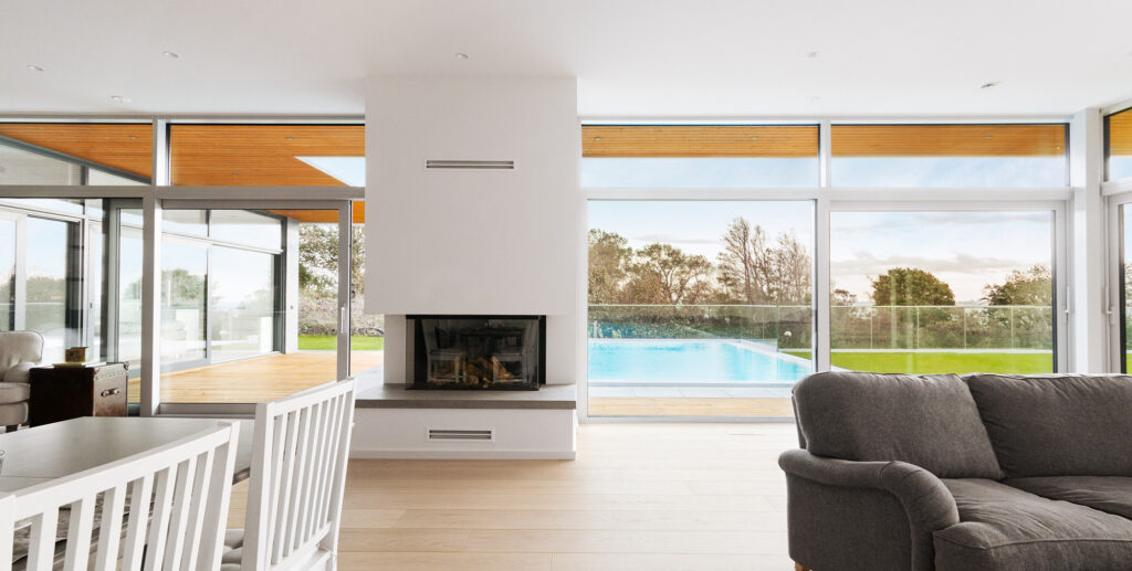 Modern living room with fireplace and full-height glazing opening to pool and terrace in Sweden