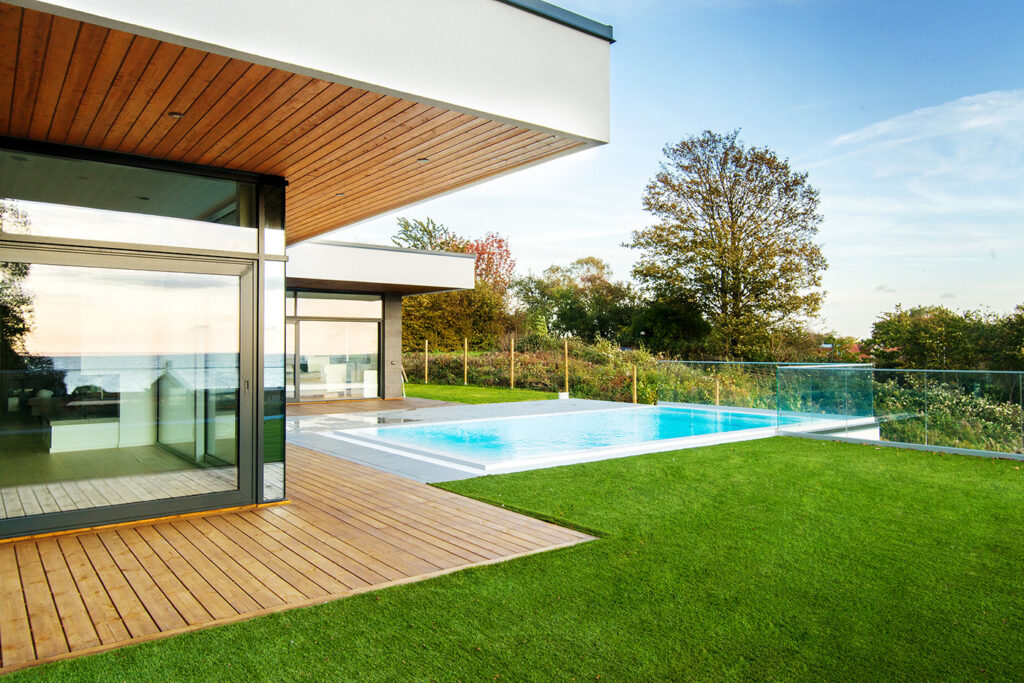 Modern courtyard villa with pool, timber terrace, and glass façade overlooking landscape in Sweden