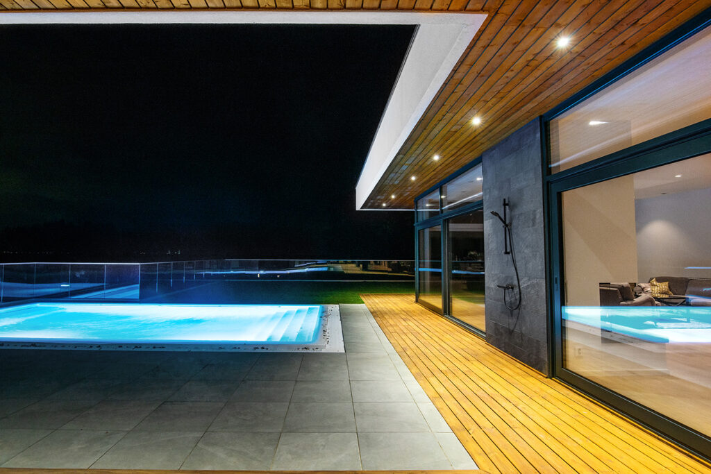 Modern courtyard villa in Sweden with illuminated swimming pool and glass façade at night